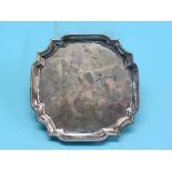 A George II silver card tray, square with re-entrant corners, on four scroll feet, formerly