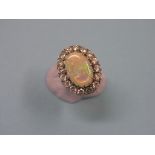A large 18ct. gold black opal and diamond dress ring, central oval opal surrounded by sixteen claw-