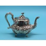 A rococo-style silver plated teapot, elaborately embossed with foliage and masks, scroll handle