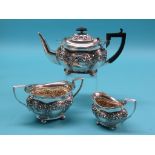 An Edward VII silver three-piece teaset, teapot with black wood handle, elaborately embossed with