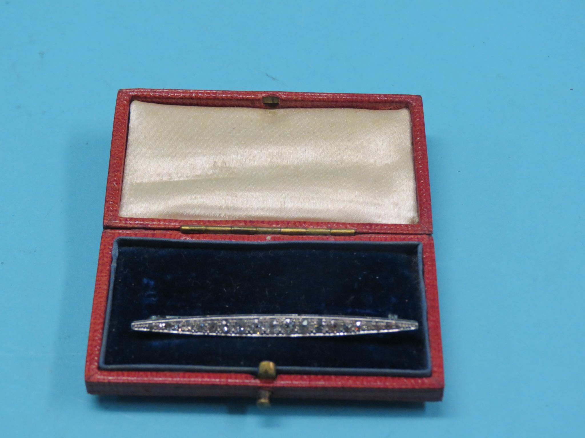 A white metal and diamond bar brooch, small graduated diamonds, metal unmarked, within original