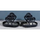 A pair of late Victorian black painted cast iron boot scrapers, twin scrolled supports and oval tray