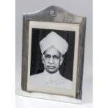 An Indian plain silvery metal rectangular photograph frame with arched top, with floral cast motif
