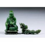 A Chinese carved and polished green stone figure of the seated Buddha holding a fruit, on shaped
