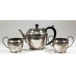 A George VI silver three piece tea service with plain circular bodies, moulded girdle and footrim,