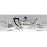 A George V silver rectangular three piece tea service with moulded collars and angular loop handles,