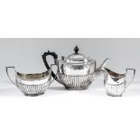 An Edward VII silver oval three piece tea service with part reeded bodies and angular loop