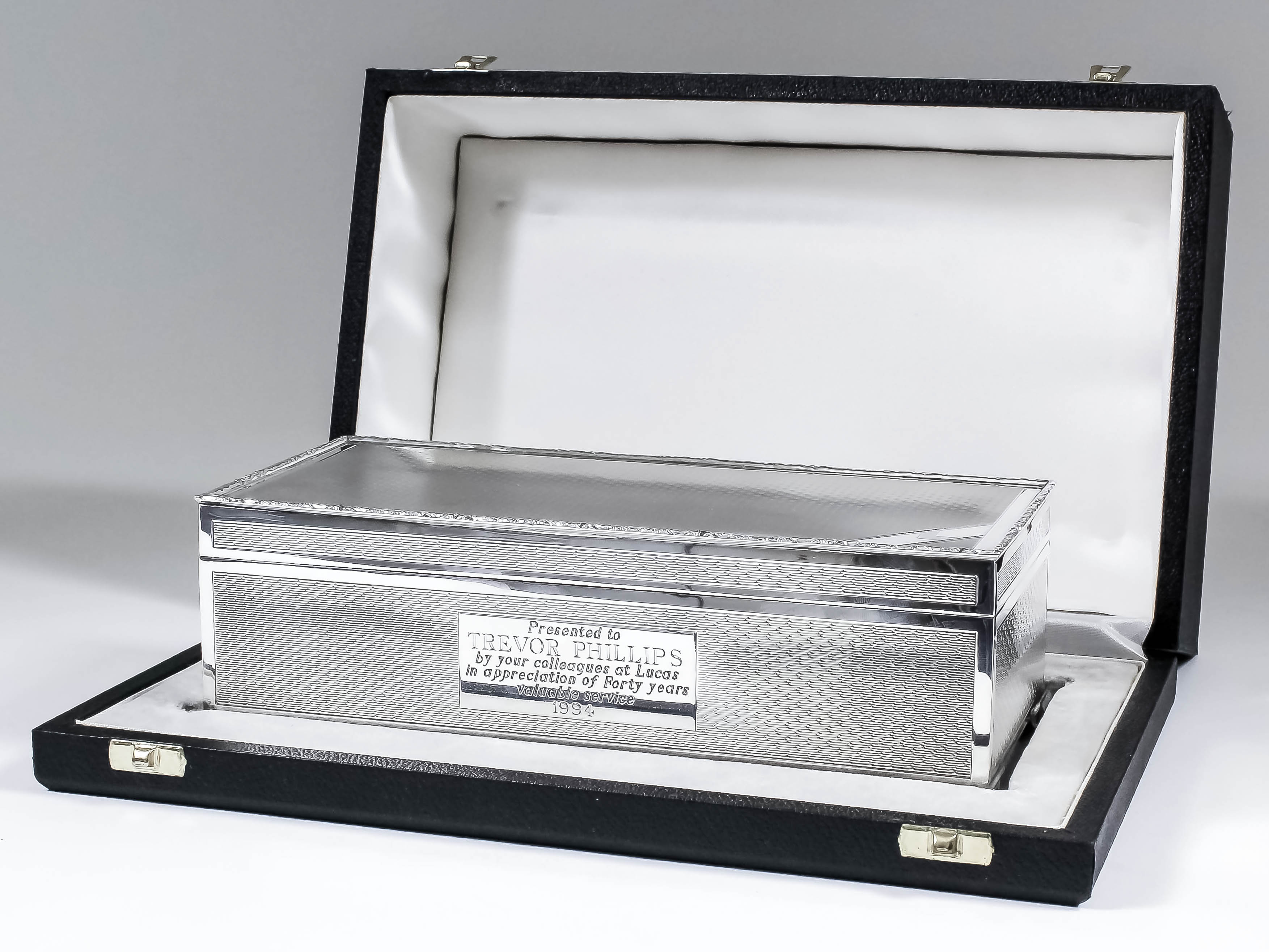 An Elizabeth II silver rectangular cigarette box with scroll cast mounts and engine turned panels to