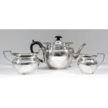 An Edward VII silver oval three piece tea service engraved with leaf scroll and floral ornament,