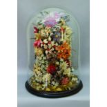 A Victorian woolwork mixed floral display contained in a cylindrical glass dome, with turned