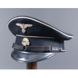 A Second World War German SS Officer's visor cap, black with white piping, bearing German eagle over