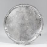A George V silver circular salver with shaped and moulded rim on three panelled feet, 10ins