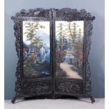 An early 20th Century Japanese ebonised framed two fold draught screen, the borders fretted and