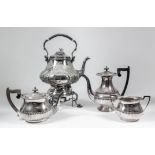 A late 19th Century plated tea kettle and stand of Rococo form, with high strap handle, the body