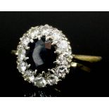 A modern 18ct gold mounted sapphire and diamond cluster ring, the oval cut sapphire of approximately