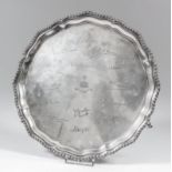 A George V silver circular salver, the shaped and moulded rim with gadroon mounts, on three scroll