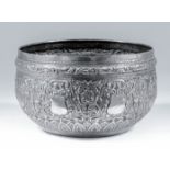 An Eastern silvery metal circular bowl embossed with eight vacant cartouches, and leaf scroll