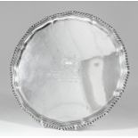 A George V silver circular salver, the shaped and moulded rim with gadroon mounts and on four claw