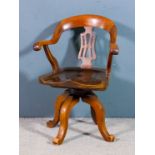 A Victorian mahogany swivel desk chair with shaped back, fretted splat, and dished wood seat, on