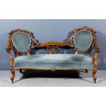 A Victorian walnut framed three seat settee, the moulded showwood frame fretted and carved with leaf