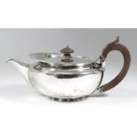 A George III plain silver teapot of squat circular form with fruitwood handle and turned finial,