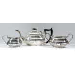 A George V harlequin silver rectangular three piece tea service with part reeded bodies,