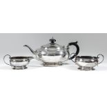 A George V silver oval three piece tea service of bulbous squat form with reeded rims and leaf