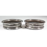 A pair of George III silver circular coasters with French gadroon mounts to rim and embossed