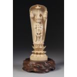 A JAPANESE MEIJI PERIOD ONE PIECE CARVED IVORY OKIMONO OF A BUDDHIST DEITY standing in a niche