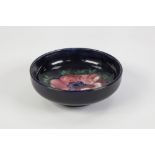 WALTER MOORCROFT ANENOME PATTERN TUBE LINED POTTERY DISH, of shallow, footed form, decorated in