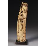 AN AGED CHINESE ONE PIECE CARVED IVORY FIGURE OF GUANYIN, a small deity figure held in her arms