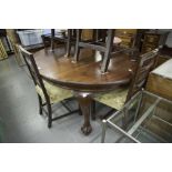 AN EARLY TWENTIETH CENTURY D-END DINING TABLE, EXTENDING WITH A WINDING ACTION, ON FOUR CARVED