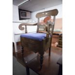 A DARK WOOD COMMODE CHAIR, SINGLE BACK RAIL SUPPORTS, SCROLL ARMS, PAD FEET ON TURNED FRONT SUPPORTS