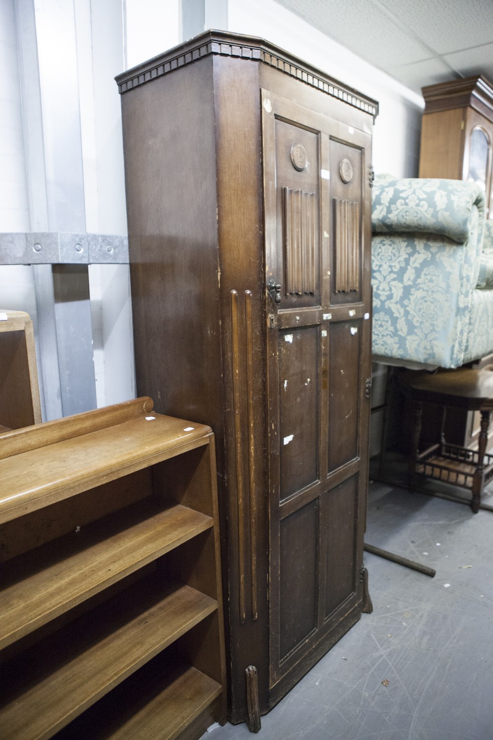 A MID TWENTIETH CENTURY DARK OAK HALLROBE, DENTIL CORNICE, OVER CANTED CORNERS, THE PANELLED DOORS