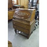 A GOOD QUALITY CARVED OAK BUREAU, THE INTERIOR WITH AUTOMATICALLY ADVANCING STATIONERY