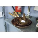 THREE GRADUATED COPPER FRYING PANS, WITH TURNED WOODEN HANDLES AND A WOODEN MORTAR AND PESTLE