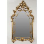 MODERN ROCOCO STYLE GILT FRAMED WALL MIRROR, the arched, oblong plate in an ornate moulded frame