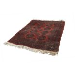 TURKOMAN BOKHARA RUG, with two rows of large stencilled black guls on a crimson field, multiple