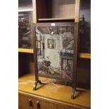 A VICTORIAN FIRE SCREEN, OAK FRAME WITH NEEDLEWORK SCENE OF A SEATED WOMAN READING