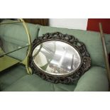OVAL BEVELLED EDGE WALL MIRROR IN A CARVED AND PIERCED OAK FRAME OF FOLIATE SCROLL AND SHELL DESIGN