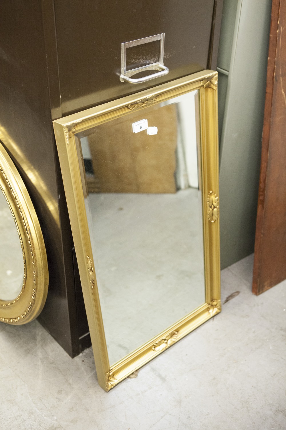 AN OBLONG BEVELLED WALL MIRROR, IN FLORAL EMBOSSED GILT FRAME, 28" X 17" OVERALL