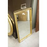 AN OBLONG BEVELLED WALL MIRROR, IN FLORAL EMBOSSED GILT FRAME, 28" X 17" OVERALL