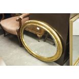 AN OVAL BEVELLED EDGE WALL MIRROR, IN GILT CAVETTO FRAME