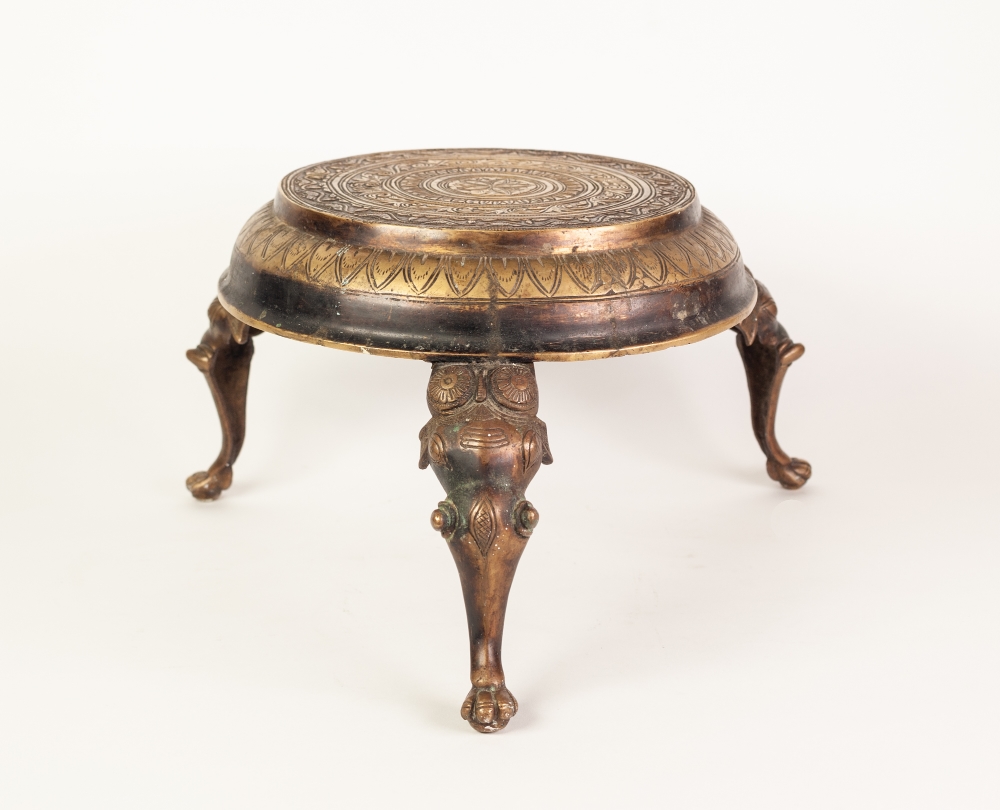 INDIAN CAST AND ENGRAVED BRASS THREE LEGGED STAND, the circular top profusely decorated with bands