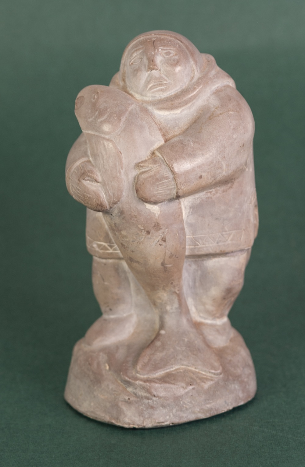 A CANADIAN INUIT STONE CARVING of an Inuit holding a large fish, incised 'Abbott, Canada', 6 1/2" (