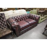 A MODERN BROWN LEATHER TWO SEATER CHESTERFIELD SOFA (WORN)