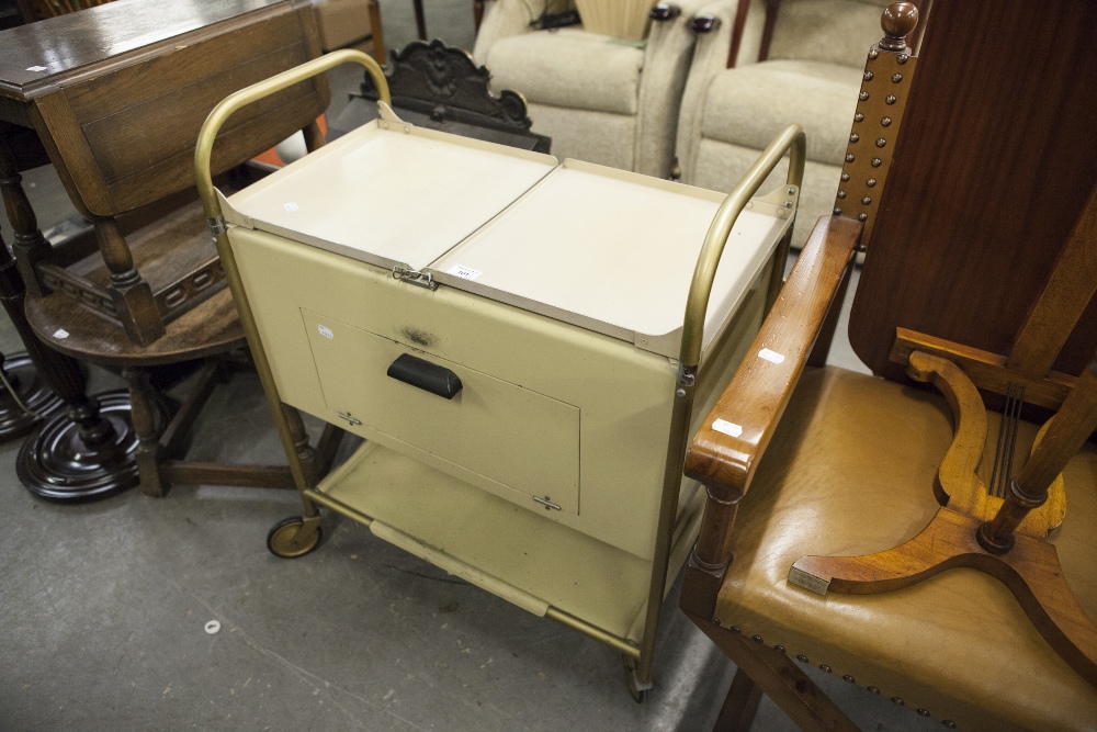 AN EARLY 1960'S CREAM ENAMEL AND GILT TUBULAR METAL HEATED FOOD TROLLEY, WITH ORIGINAL LIDDED DISHES