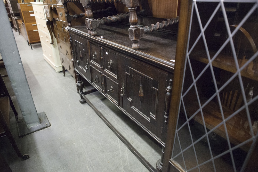 A JACOBEAN STYLE CARVED OAK SIDEBOARD WITH LEDGE BACK AND METAL PEAR SHAPED DROP HANDLES