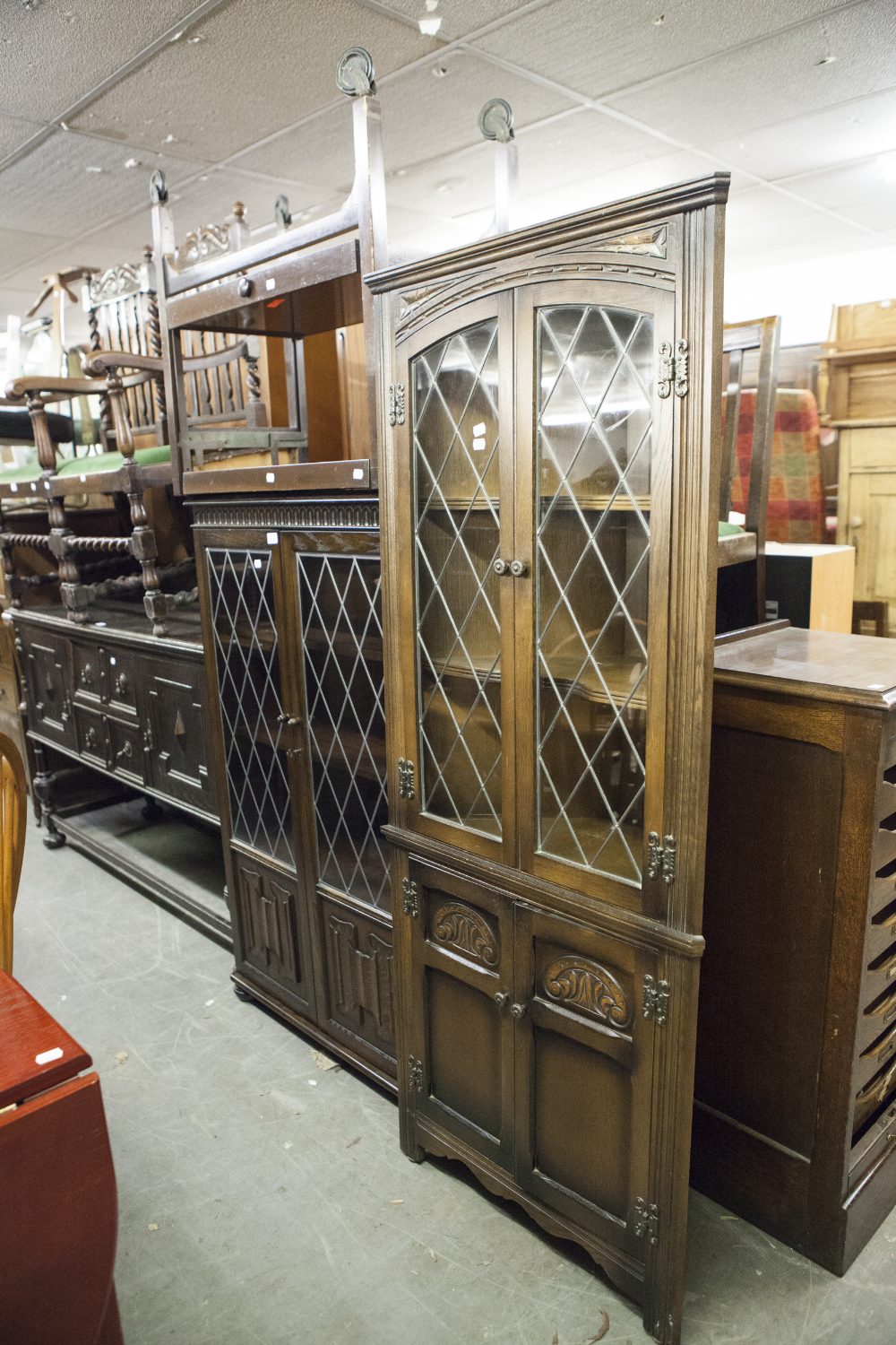 AN 'OLD CHARM' REPRODUCTION DARK OAK DISPLAY CABINET WITH LEADED GLAZED DOORS OVER LINEN FOLD