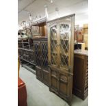 AN 'OLD CHARM' REPRODUCTION DARK OAK DISPLAY CABINET WITH LEADED GLAZED DOORS OVER LINEN FOLD